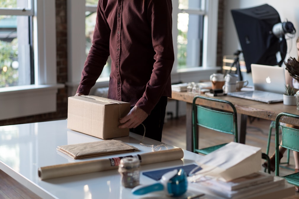 Person holding a cardboard shipping box ready to pack an order